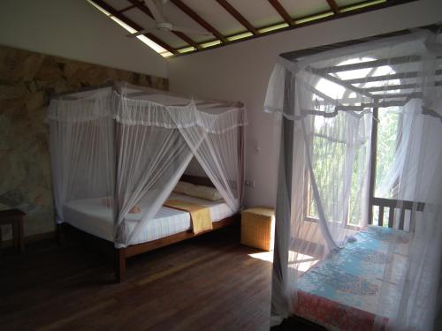 sypialnia z łóżkiem z baldachimem i oknem w obiekcie Coconut Island w Tangalli
