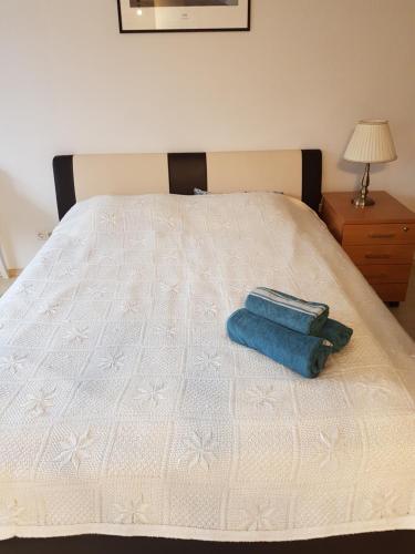 a white bed with a blue towel on it at Scandinavian Breeze Apartment in Klaipėda