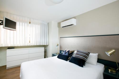 a bedroom with a large white bed with blue pillows at Marine Heights Suites in Herzliya