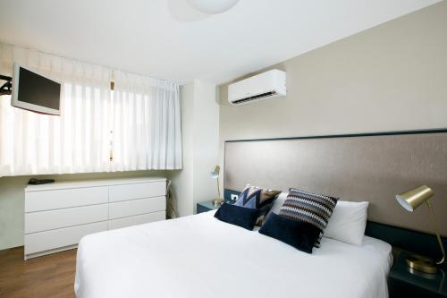 a bedroom with a large white bed with blue pillows at Marine Heights Suites in Herzelia 