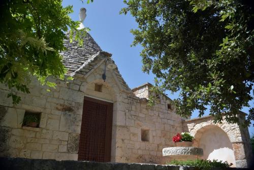 an old stone building with a door and a flower pot at Vacanza In Puglia in Alberobello