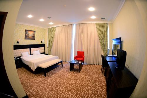a bedroom with a bed and a red chair at New Baku Hotel in Baku