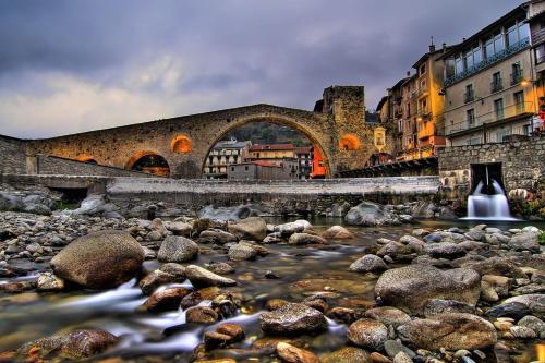 a river with rocks and a bridge and buildings at Hotel Grèvol Spa in Camprodon