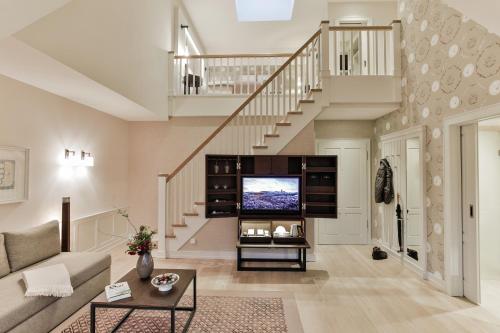 a living room with a tv and a staircase at Severin's Resort & Spa in Keitum