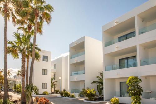 ein Apartmenthaus mit Palmen davor in der Unterkunft Oasis Lanz Beach Mate in Costa Teguise