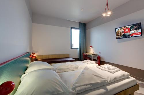 a bedroom with a large bed with white sheets at MEININGER Hotel Paris Porte de Vincennes in Paris