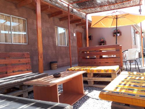 uma sala com bancos, uma mesa e um guarda-chuva em Hostal Open House em San Pedro de Atacama
