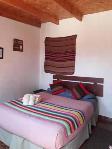 a bedroom with a bed with a colorful blanket at Hostal Open House in San Pedro de Atacama