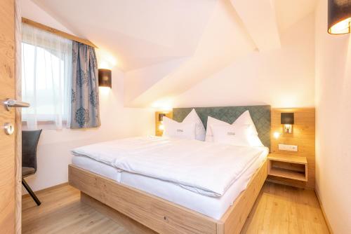 Schlafzimmer mit einem Bett mit weißer Bettwäsche und einem Fenster in der Unterkunft Obergrundhof in Leogang
