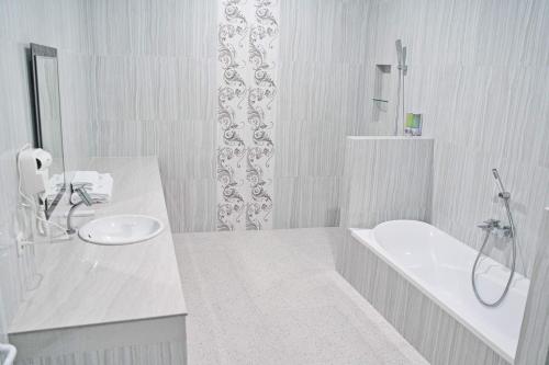 Baño blanco con bañera y lavamanos en Seamount Hotel Amed en Amed