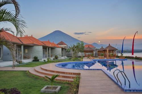 a resort with a pool and a mountain in the background at Seamount Hotel Amed in Amed