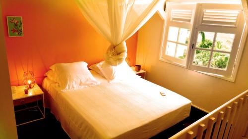 a bedroom with a white bed with a window at Duplex 4 personnes Chambre vue mer Résidence O Coeur de Deshaies in Deshaies