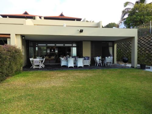 a patio with white tables and chairs on a house at 1 Marichel in Ballito