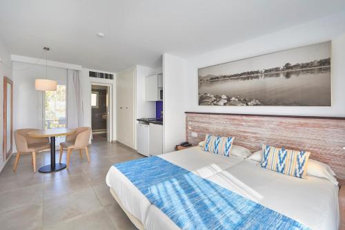 a bedroom with a bed and a table in it at Seaclub Alcudia Mediterranean Resort in Port d'Alcudia