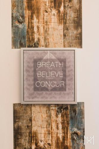 a sign that reads breath believe comfort hangs on a wall at Mulberry House in Trani