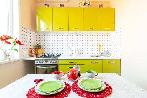 eine Küche mit gelben Schränken und einem Tisch mit Tellern in der Unterkunft Fruza family apartment in Riga in Riga