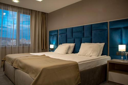 um quarto com uma cama grande e uma cabeceira azul em Grand Hotel Shumen em Shumen