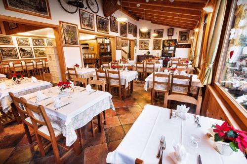 restauracja z białymi stołami i krzesłami oraz oknem w obiekcie Al Fogolar w mieście Villa Santina