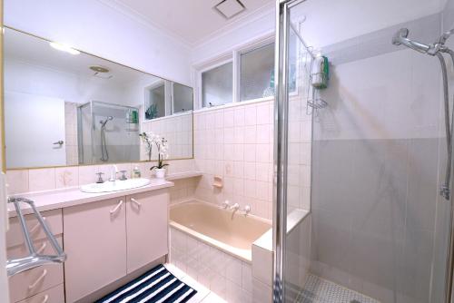 y baño con ducha, lavabo y bañera. en Family home in Prime location Melbourne, en Fern Tree Gully