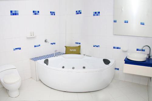 een witte badkamer met een bad en een toilet bij Ayenda 1801 El Oceano in Cartagena