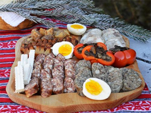 a plate of food with eggs and meats on a table at Cabana Poiana Dealul Frumos in Gîrda de Sus