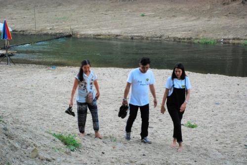 three people walking on a beach near a body of water at Baantantara in Suan Phung