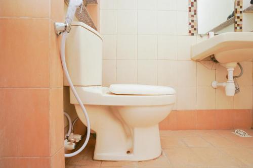 La salle de bains est pourvue de toilettes blanches et d'un lavabo. dans l'établissement SUPER OYO 2075 Graha Marina, à Surabaya