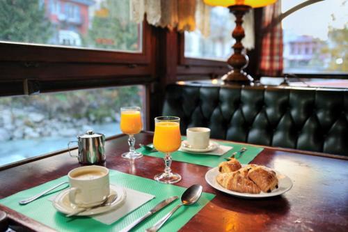a table with a plate of food and two glasses of orange juice at Hôtel Vallée Blanche in Chamonix
