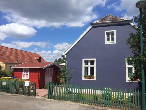 ein blaues Haus mit einem Zaun vor einem roten Haus in der Unterkunft Ferienhaus Niemtsch in Niemtsch