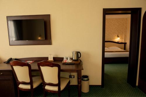 a hotel room with a table and chairs and a bed at Magus Hotel in Baia Mare