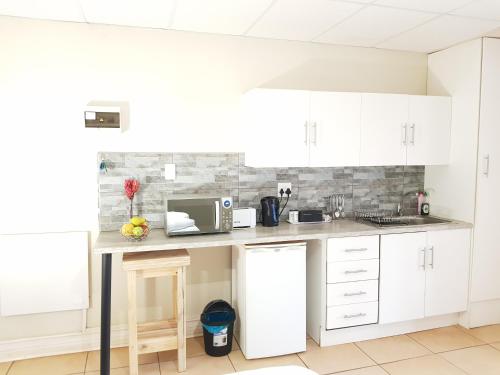 a kitchen with white cabinets and a microwave at CHEETAH MANOR #4 in Bloemfontein