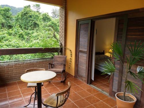 a balcony with a table and chairs and a window at Solar das Canoas Prumirim in Ubatuba