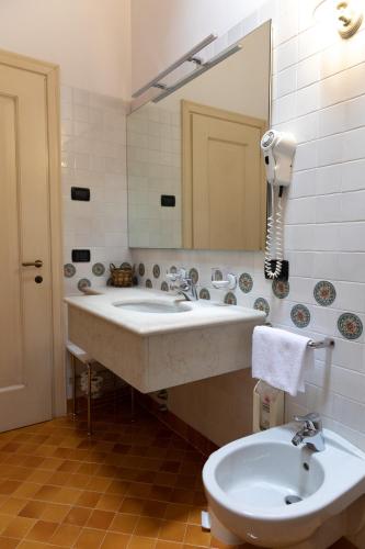 a bathroom with a sink and a mirror and a toilet at Hotel Locanda Al Sole in Castello di Godego