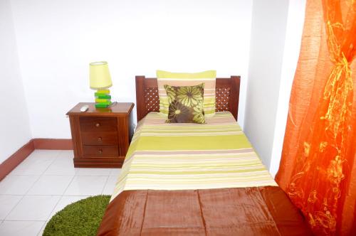 a small bedroom with a bed and a night stand at Ana Chaves Residence in São Tomé