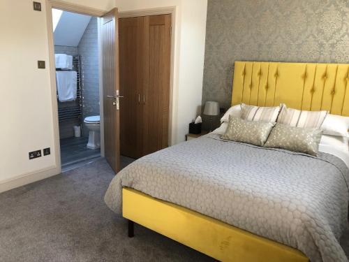 a bedroom with a large bed with a yellow headboard at Christmas Hill Farm in Gaydon