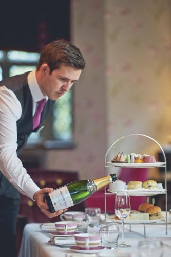 a man pouring a bottle of wine on a table at Great Fosters - Near Windsor in Egham