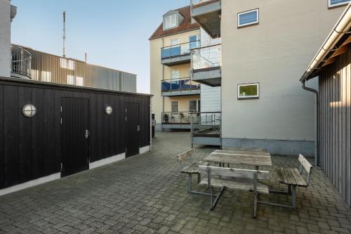 a patio with a wooden table and benches on a building at Harbour Penthouse in Sønderborg