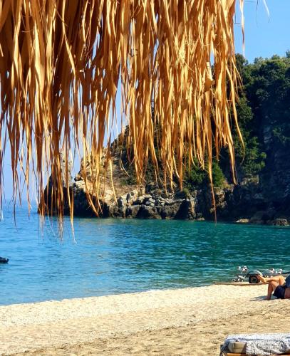 a beach with a straw umbrella and the water at Aeolos Hotel & Villas - Pelion in Chorefto
