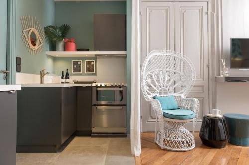 a kitchen with a white chair with a blue pillow at MiHotel Gailleton in Lyon