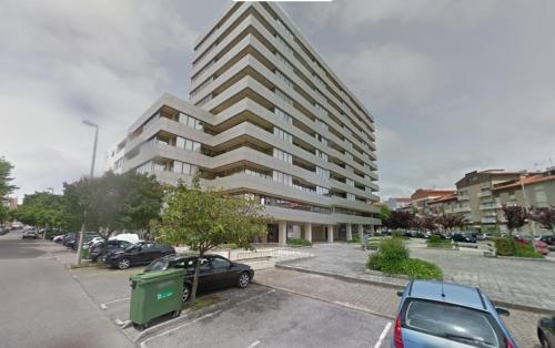 un gran edificio con coches estacionados en un estacionamiento en A MINHA ALEGRE CASINHA en Aveiro