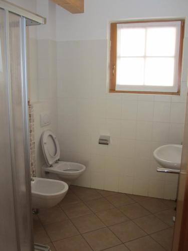 a bathroom with a toilet and two sinks and a window at La Pezina in Livigno
