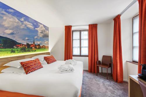 ein Schlafzimmer mit einem weißen Bett und einem Gemälde an der Wand in der Unterkunft Hotel KLE, BW Signature Collection in Kaysersberg
