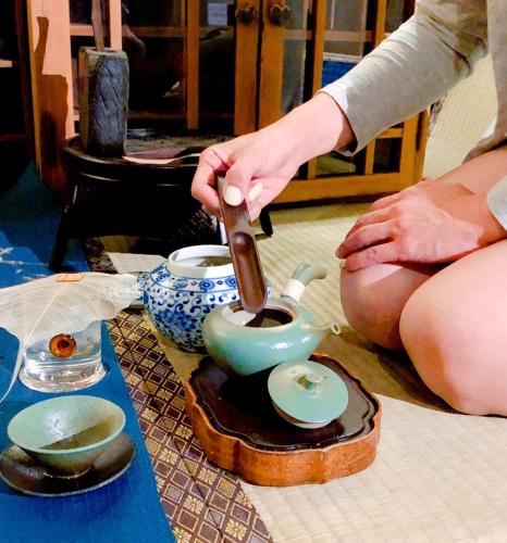 a person pouring tea into a teapot on a table at 台甕茶室青年旅館 Tai-Wong Tatami Room Hostel in Tainan