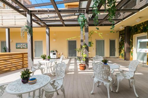 un patio con mesas blancas, sillas y plantas en Borghetto Guest House, en Roma