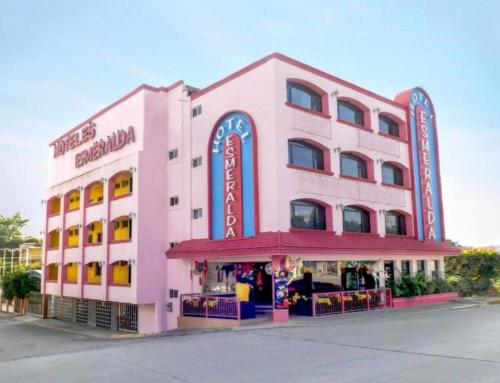 a pink building with a restaurant in front of it at Hotel Esmeralda in Poza Rica de Hidalgo