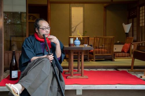 a man sitting on a table with a microphone at 伝心庵 Garden Villa Denshin-An in Kyoto