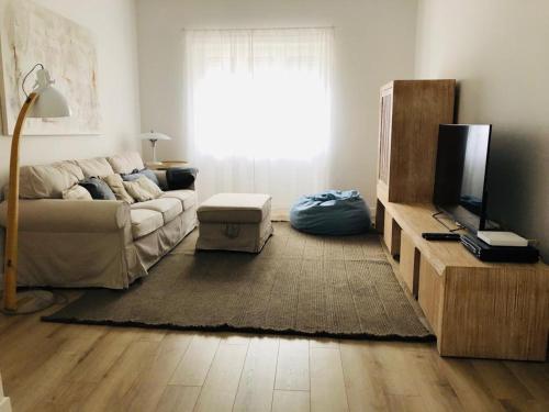 a living room with a couch and a television at Apartamento espaçoso e confortável no centro do Montijo in Montijo