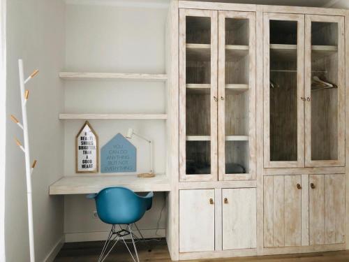 une armoire en bois dans une pièce avec une chaise bleue dans l'établissement Apartamento espaçoso e confortável no centro do Montijo, à Montijo