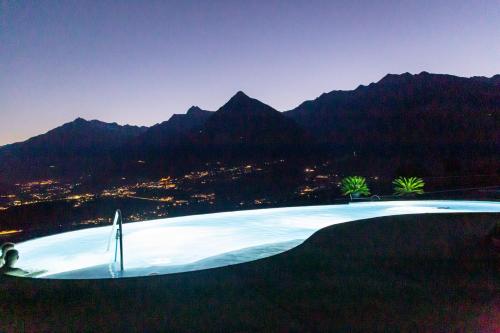 a large swimming pool with mountains in the background at Pension Obertaberhof in Schenna