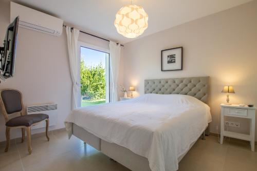 ein weißes Schlafzimmer mit einem Bett und einem Fenster in der Unterkunft La Gaoute in Sainte-Maxime